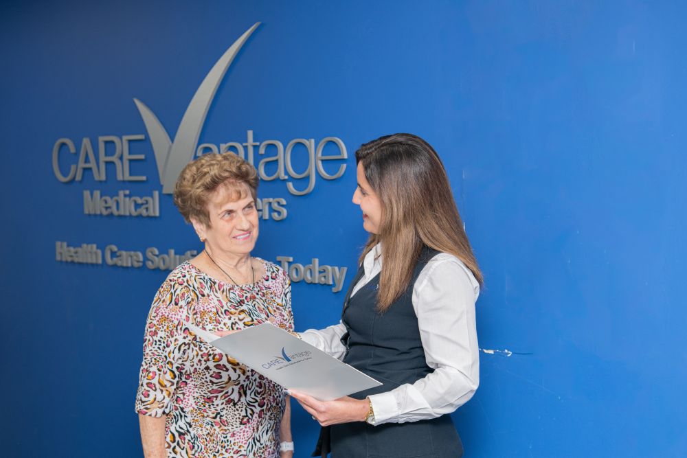 Two people in front of a blue CareVantage wall