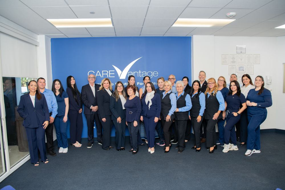 A group of people gathered in front of a blue CareVantage wall